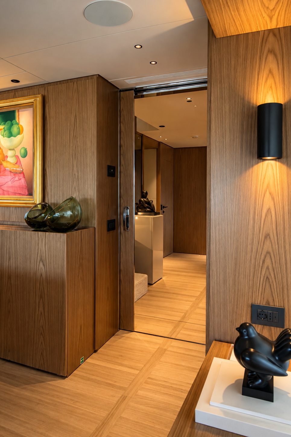Corridor with a colourful painting, a dark sculpture on a plinth and a wall light