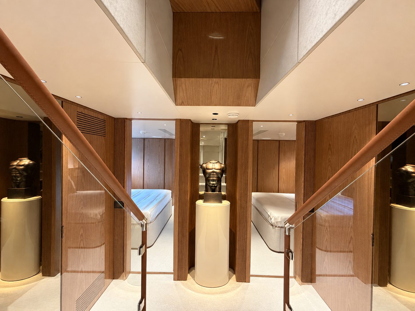 Staircase landing with leather-clad handrails, oak doors to the guest cabins and two sculptures on plinths