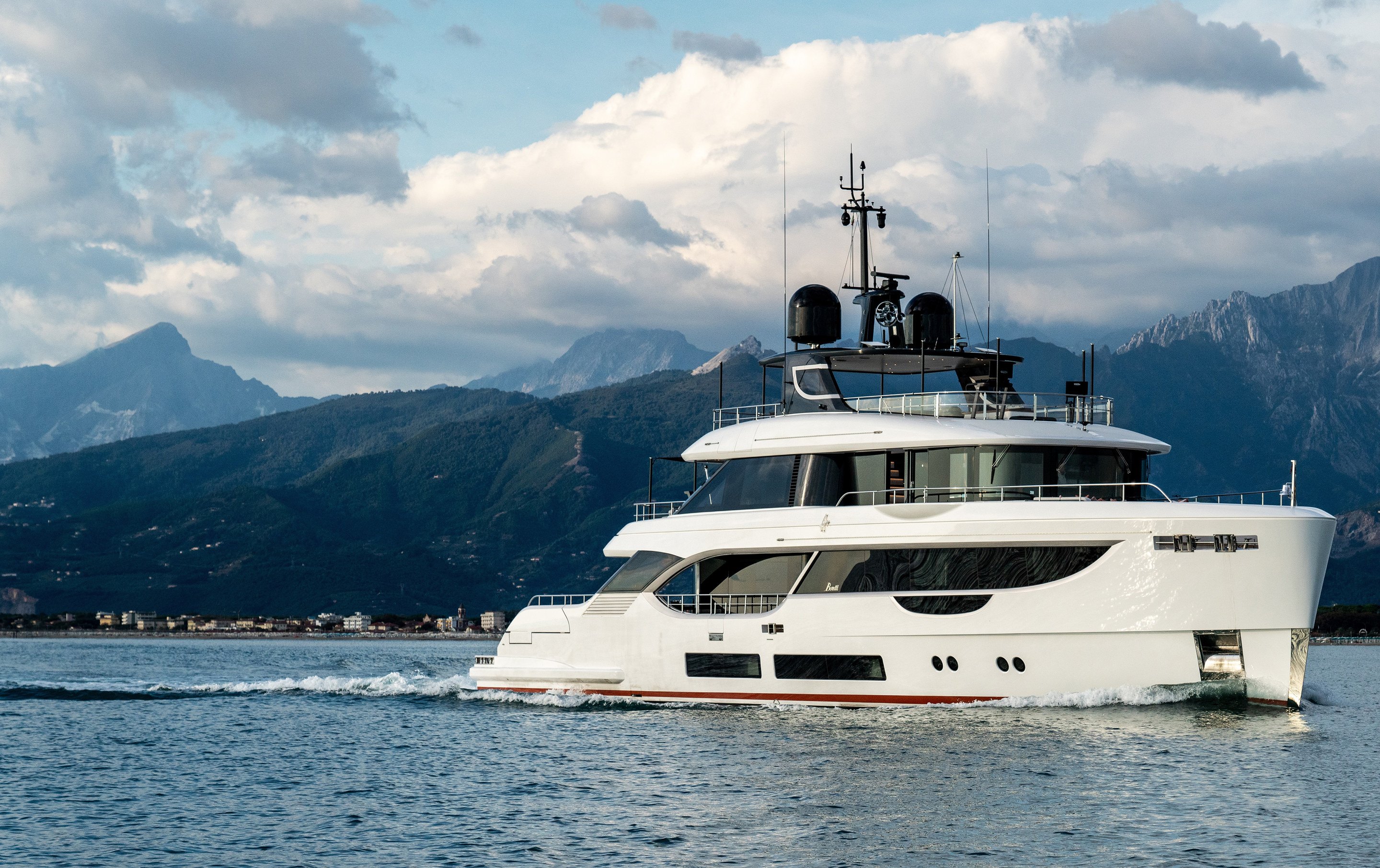 The motor yacht A+ under way along a mountainous coastline